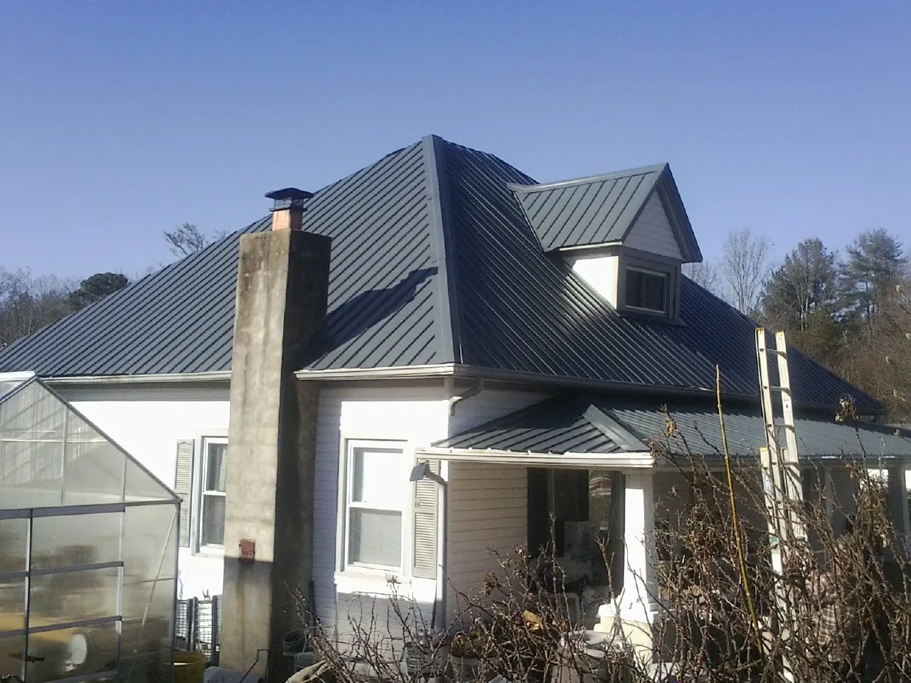 Dark blue standing seam metal roof on a white farmhouse with dormer — Slate & Tile Roof Repair by Roofing Brothers in American Falls
