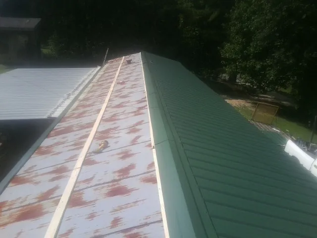 Old rusted panels beside newly installed green metal roofing — Wind Damage Roof Repair by Roofing Brothers in American Falls