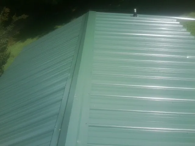 New green metal panels meeting at the ridge of a roof — Flat Roof Repair work by our crew in American Falls