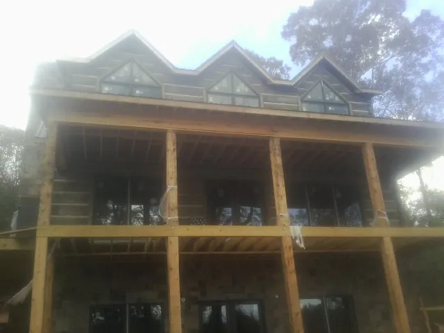 Dormers and porch framing on a large log home under construction — Roof Coating work by our crew in American Falls
