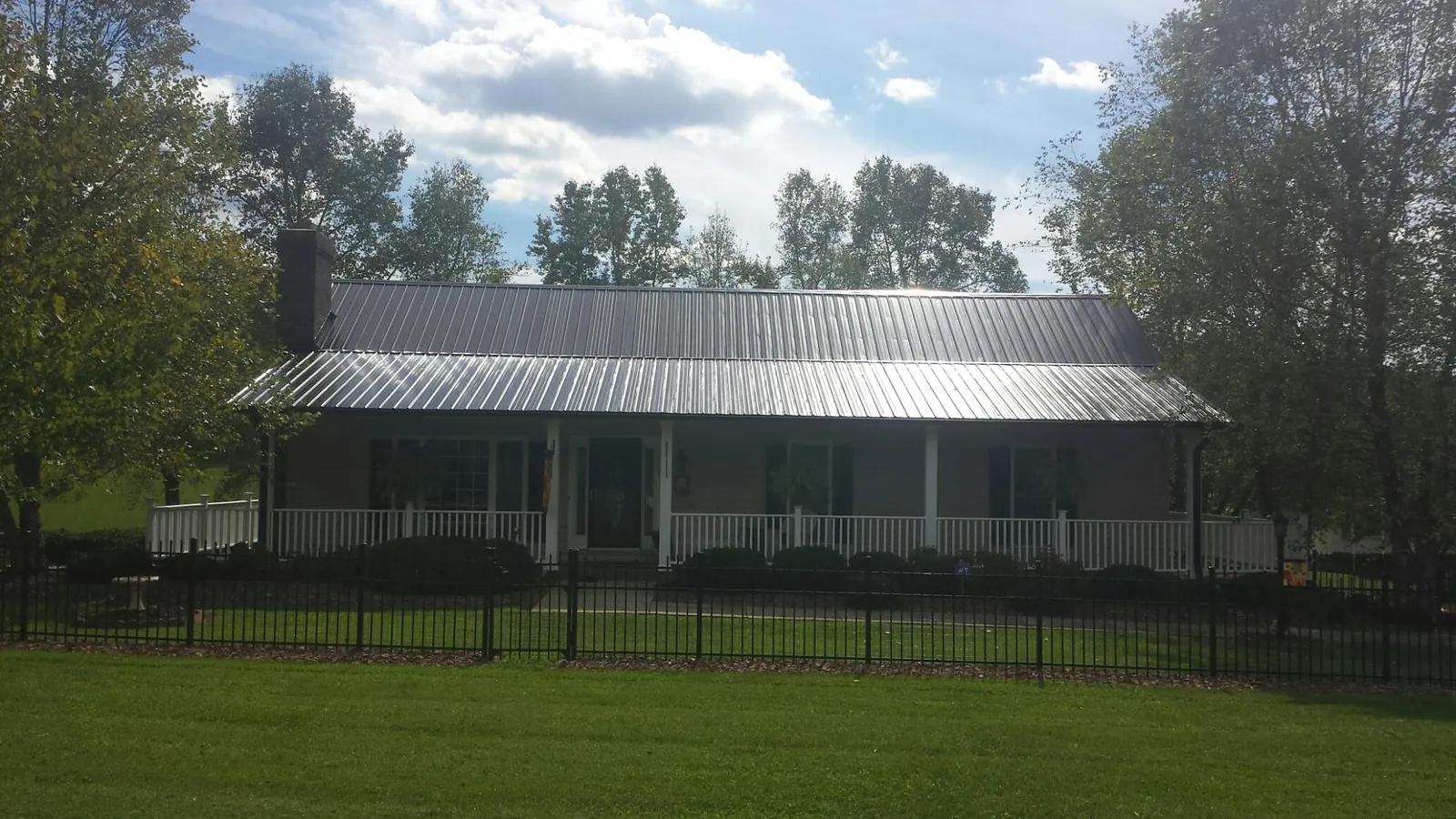 Gray metal roof on a brick ranch with a full width front porch — Gutter Guard Installation work by our crew in American Falls