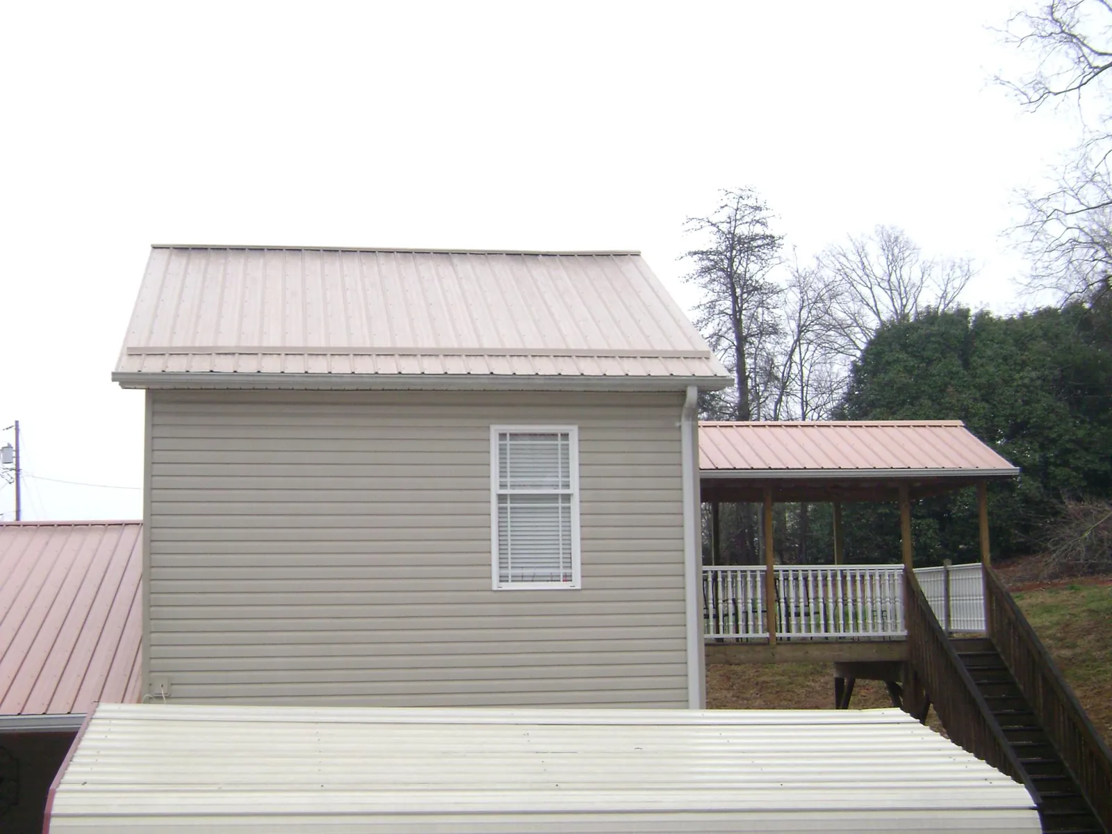 Tan metal roofs on a two story addition and attached porch, from a Roof Replacement job in American Falls
