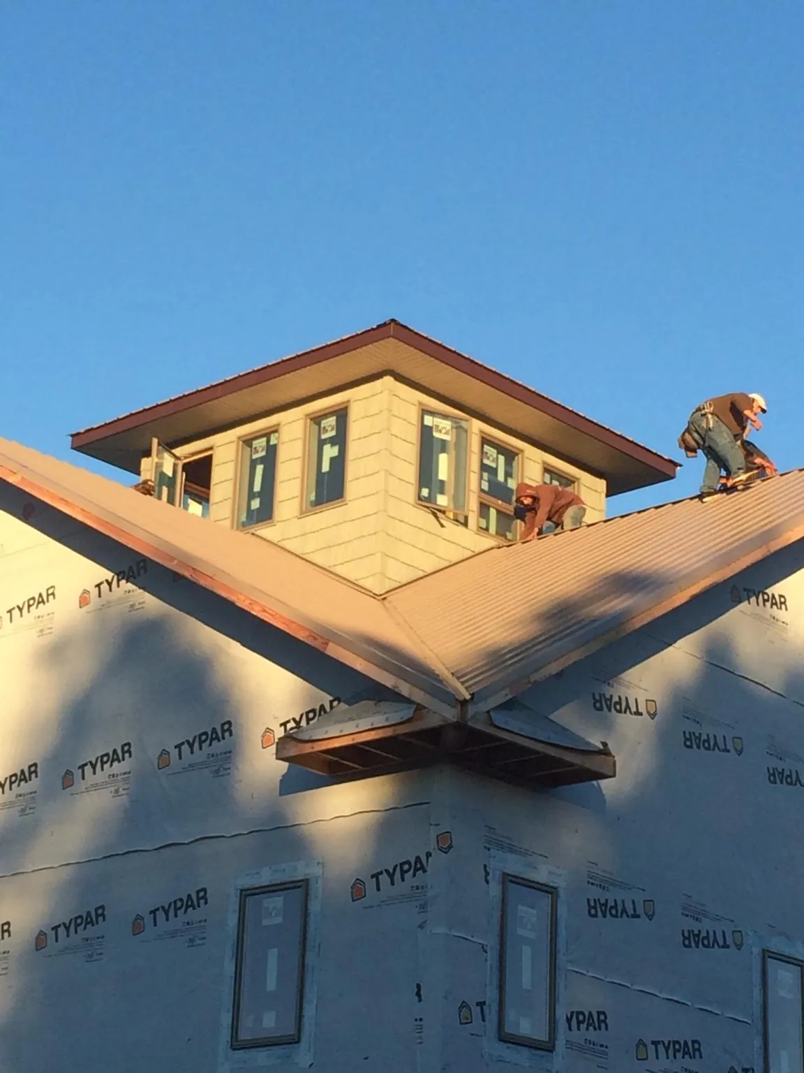Roofers working around a rooftop cupola on a new metal roof at sunset — Roof Waterproofing in American Falls by Roofing Brothers